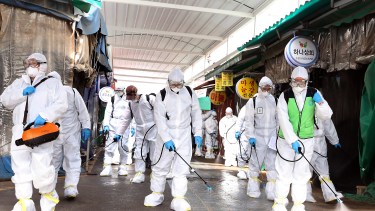 En Corea, trabajadores usan protección para desinfectar la zona de un mercado, de manera preventiva. Foto AP. 