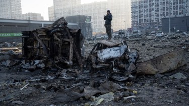 Un hombre se para sobre un automóvil destruido en medio de la destrucción causada después del bombardeo de un centro comercial, en Kiev, Ucrania (AP Photo/Rodrigo Abd)