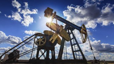 Operating oil and gas well profiled on cloudy sky